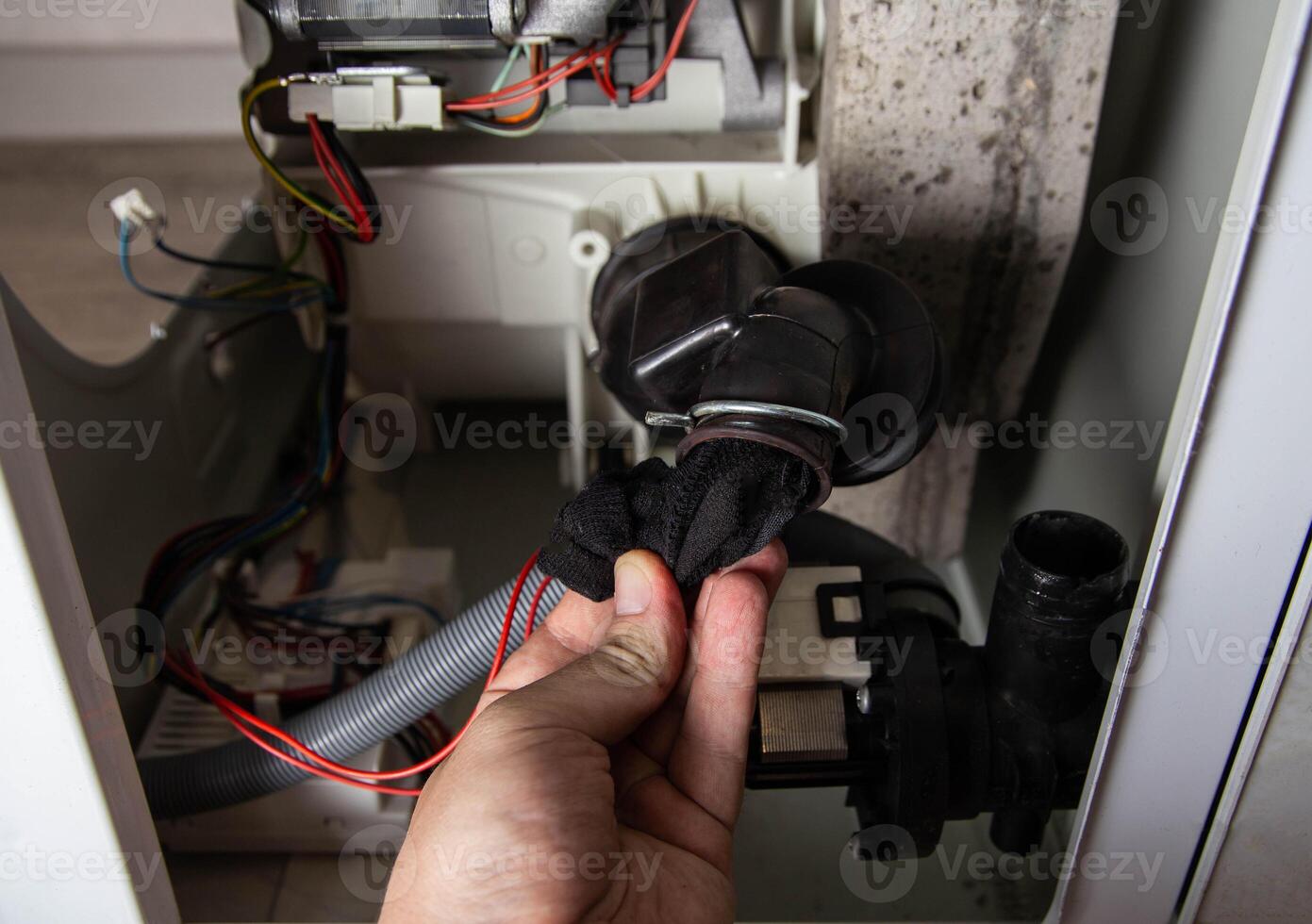 The rubber drain pipe and drain pump are clogged with clothes in the washing machine. Cleaning the water drain hole, industry photo