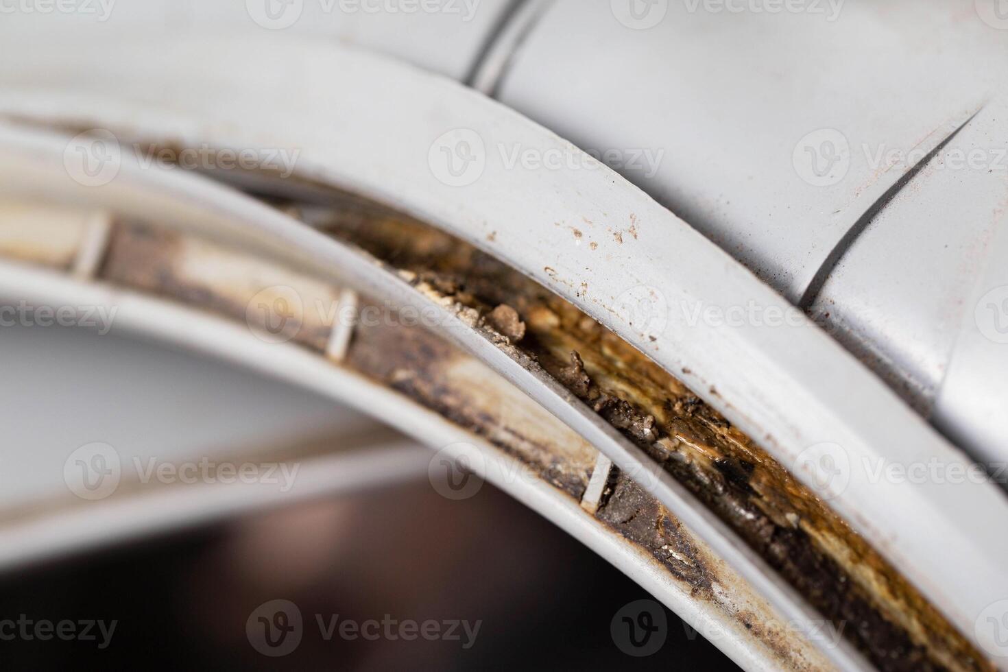Dirt, mildew and mold in the hatch seals of the washing machine. Unsanitary and unpleasant smell. Cleaning and repairing stains in the washing machine, close-up photo