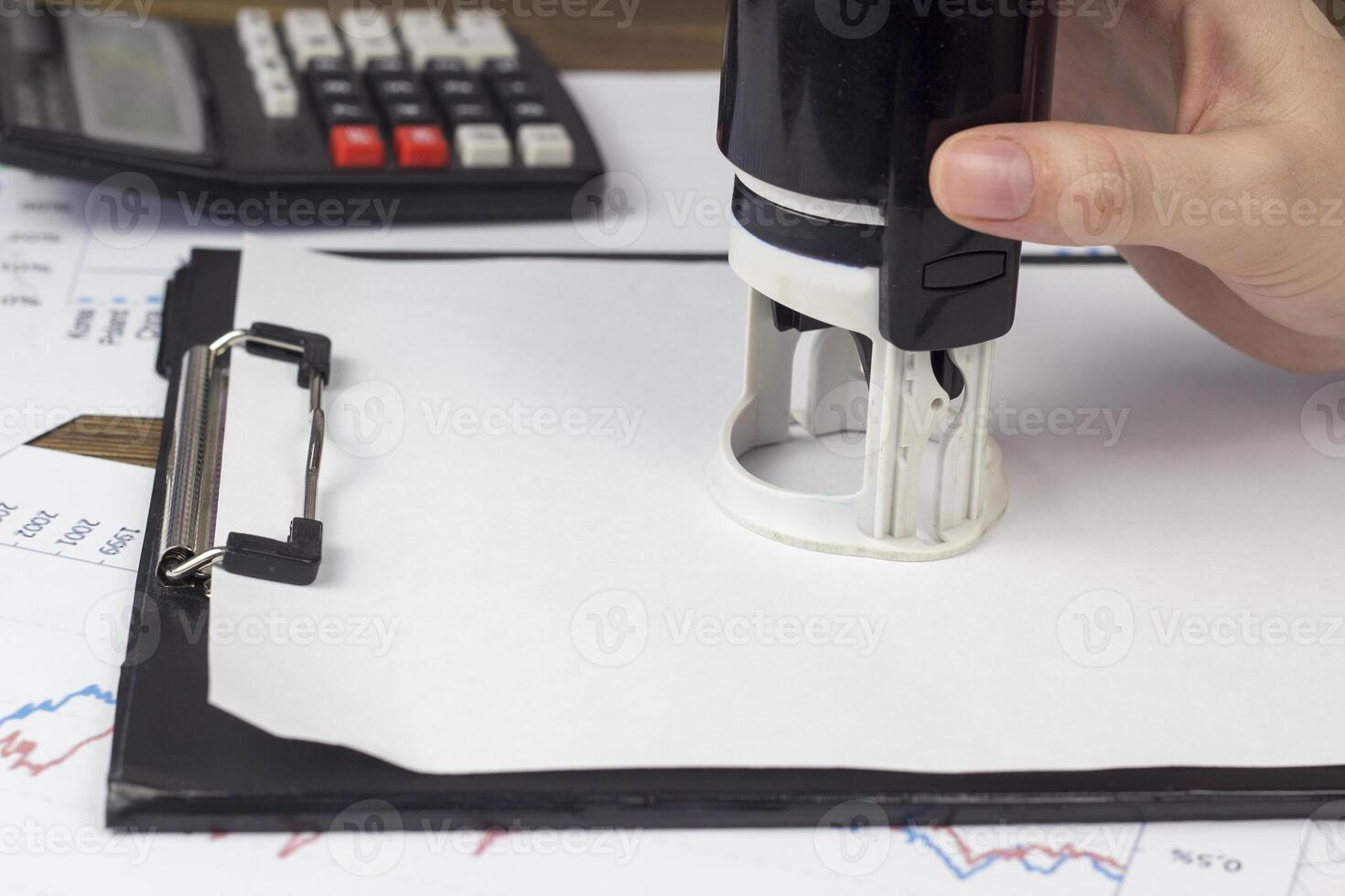 a female hand puts a seal on a blank sheet photo