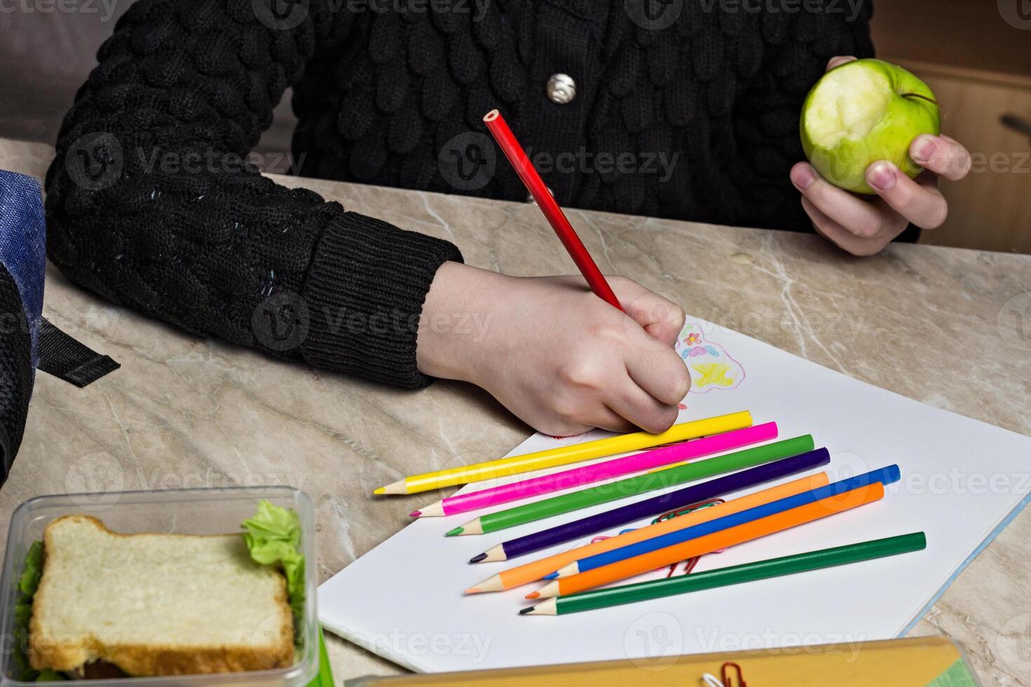 girl doing homework and eating apple, close up photo
