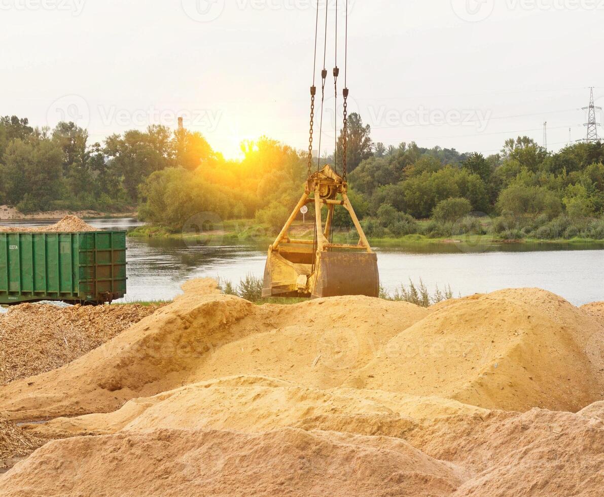 The port crane makes loading of wood chips into the freight wagons of the train, close-up, ladle photo