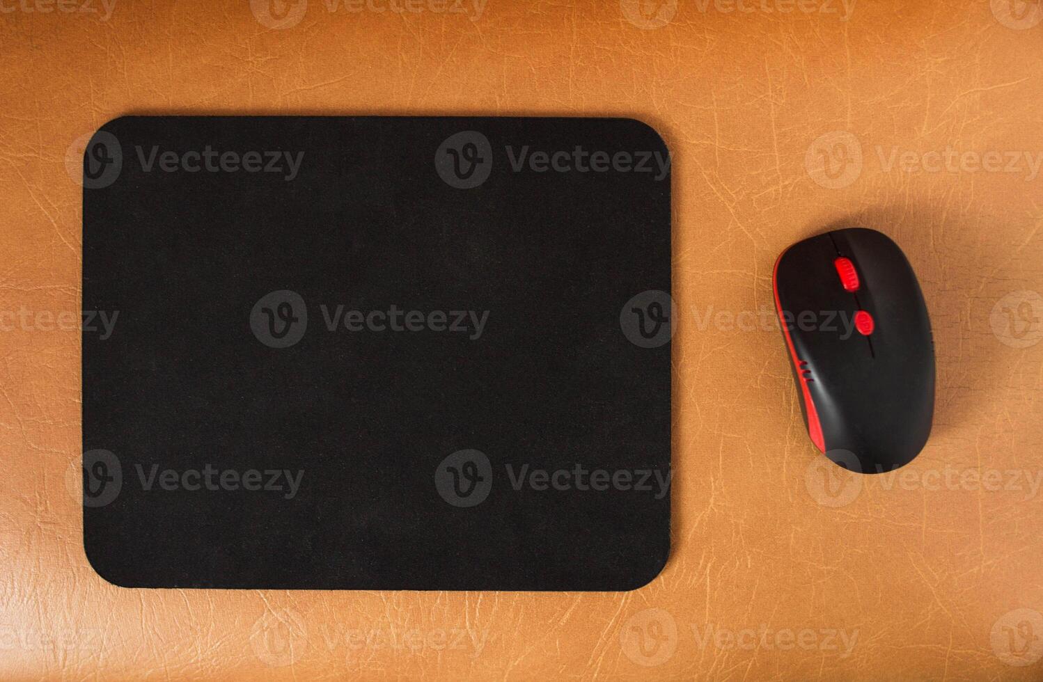 Computer mat and computer mouse on a brown leather background, close-up, modern photo