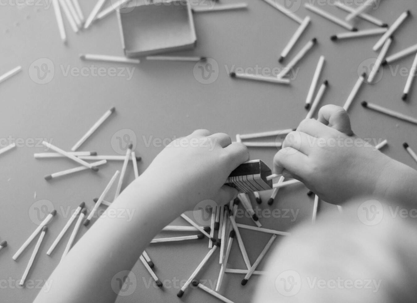 A small child plays with matches, takes matches from the table, close-up, black and white, fire, matches and child photo