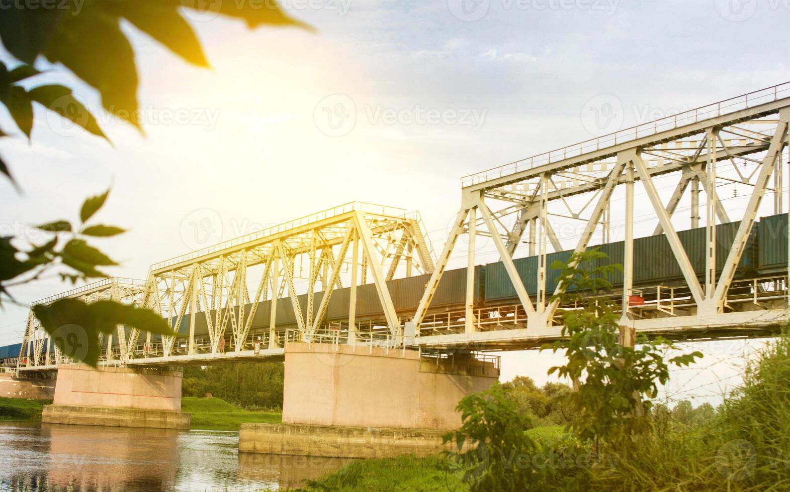 The freight train is moving along the railway bridge across the river photo