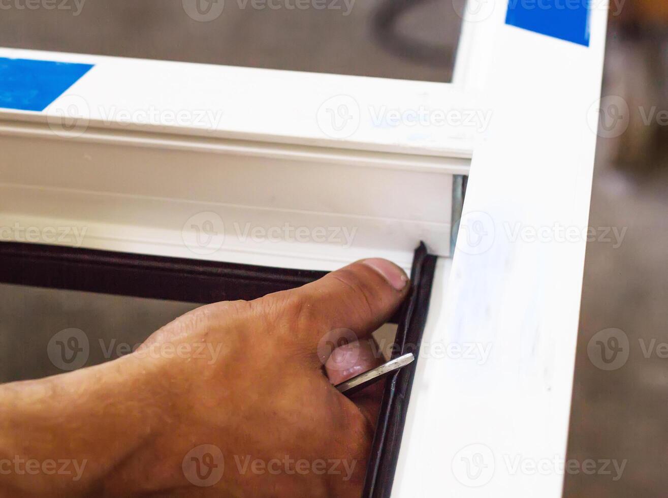 Production of pvc windows, the worker installs the sealing rubber in the pvc frame, close-up, hands photo