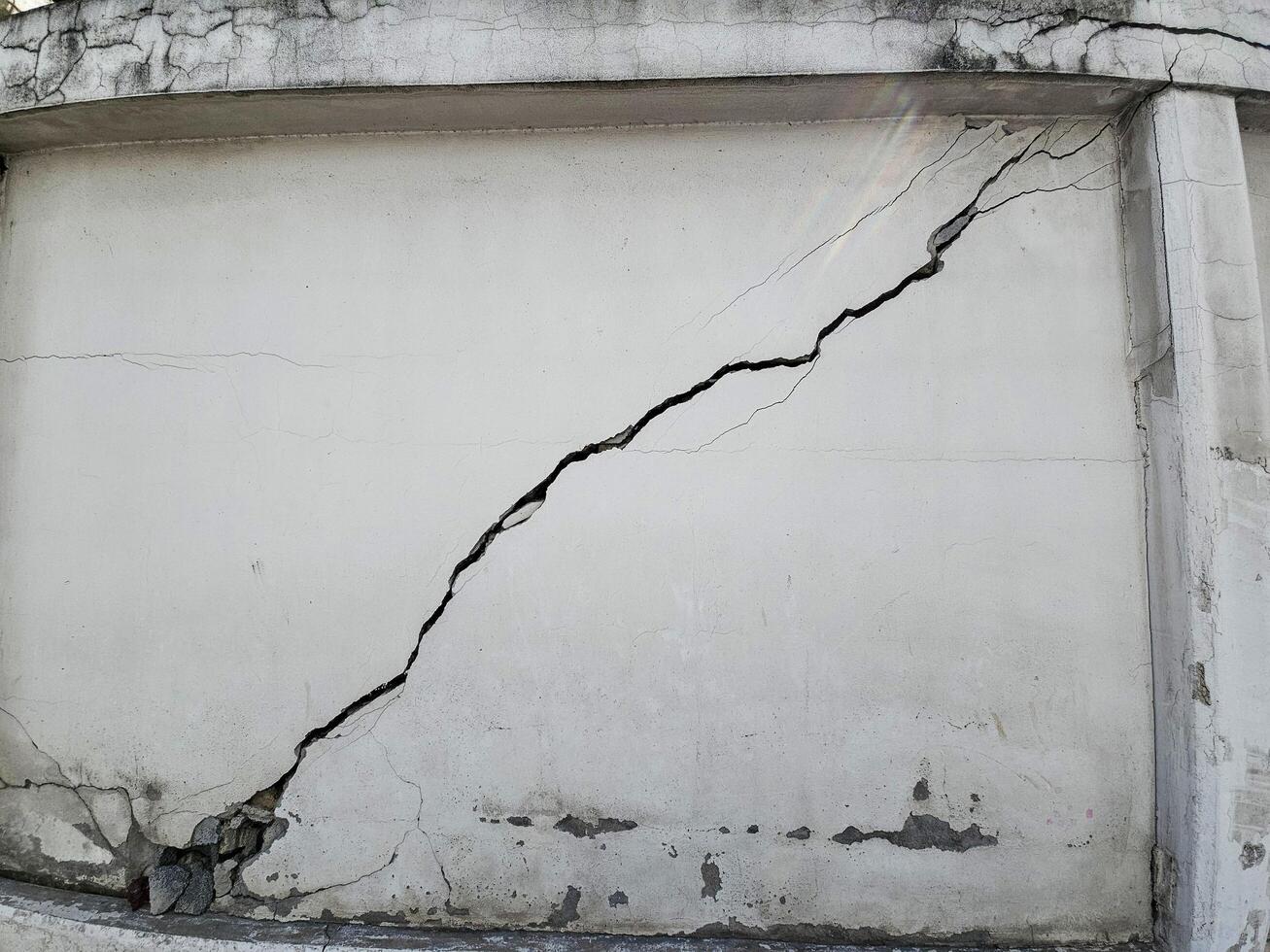 Large cracked concrete wall, a broken exterior barrier resulting from an earthquake's impact. photo