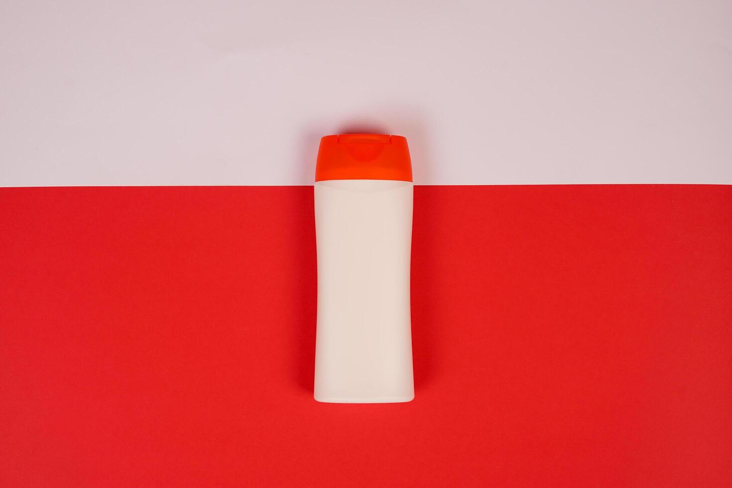 Plastic shampoo bottle with flip-top lid isolated on red and white background. MockUp template for your design. Empty and clean packaging for cosmetic product. File contains clipping path. photo