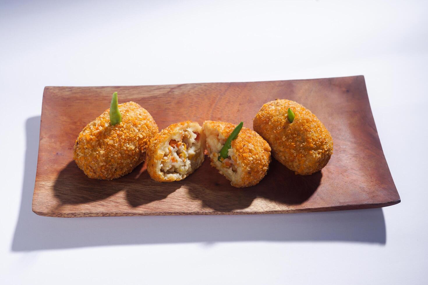 Delicious Indonesian snack named Risol or Risoles filled with smoked beef mayonnaise and crispy fried bread crumb texture on a wooden plate, isolated on a white background photo