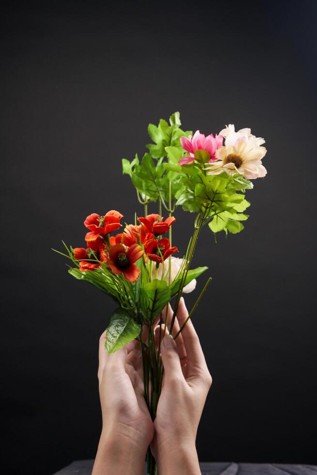 Hand holding red and white spring flowers on black background. High resolution photo. Selective focus. photo