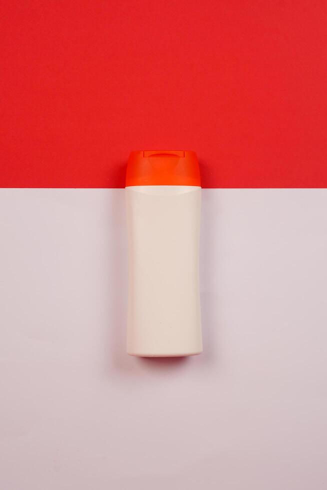 Plastic shampoo bottle with flip-top lid isolated on red and white background. MockUp template for your design. Empty and clean packaging for cosmetic product. File contains clipping path. photo
