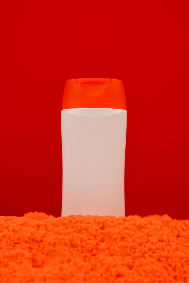 Plastic shampoo bottle with flip-top lid isolated on orange sand background. MockUp template for your design. Empty and clean packaging for cosmetic product. File contains clipping path. photo