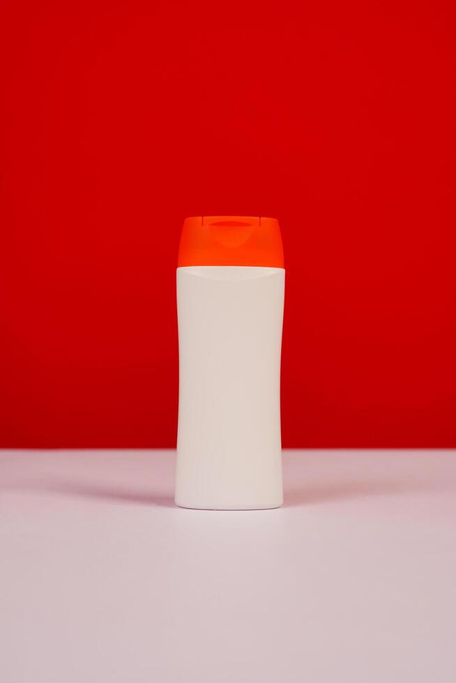 Plastic shampoo bottle with flip-top lid isolated on red and white background. MockUp template for your design. Empty and clean packaging for cosmetic product. File contains clipping path. photo
