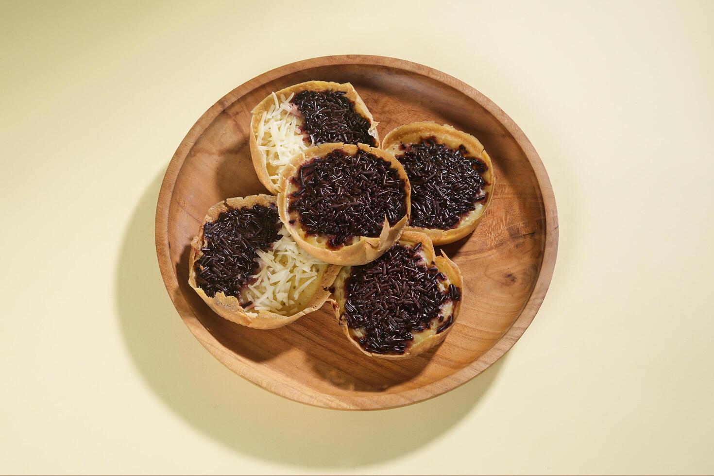 Martabak mini or terang bulan mini is Indonesian popular street food, made from flour, egg, yeast, topped with cheese or chocolate. Mini sweet martabak isolated on yellow background. photo