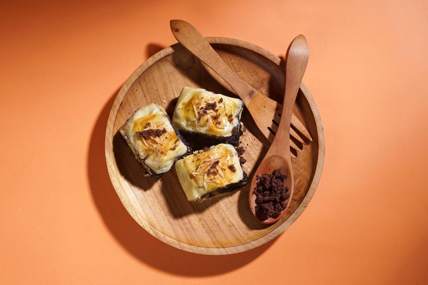 Banana Bolen is made from bananas and pastry dough, filled with chocolate and cheese. It is served on a wooden plate in a selective focus style image. photo