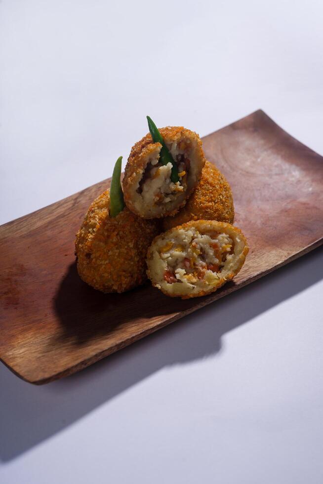 Delicious Indonesian snack named Risol or Risoles filled with smoked beef mayonnaise and crispy fried bread crumb texture on a wooden plate, isolated on a white background photo