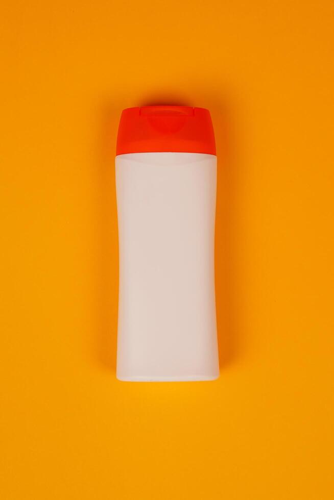 Plastic shampoo bottle with flip-top lid isolated on orange background. MockUp template for your design. Empty and clean packaging for cosmetic product. File contains clipping path. photo