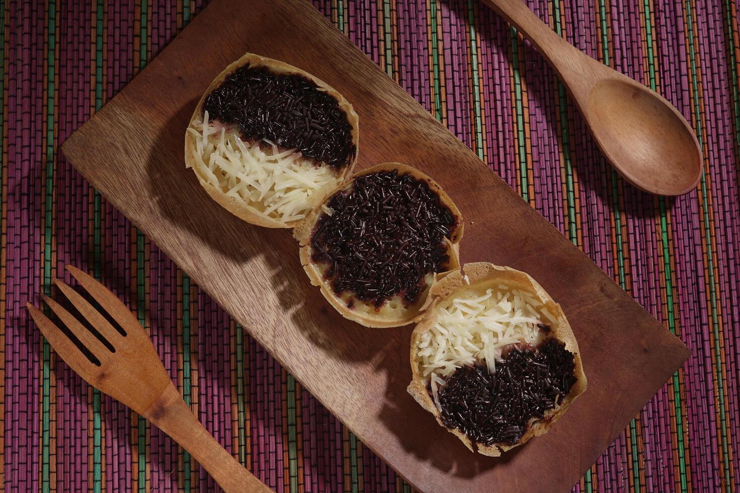 Martabak mini or terang bulan mini is Indonesian popular street food, made from flour, egg, yeast, topped with cheese or chocolate. Mini sweet martabak placed on a rainbow-colored mat photo