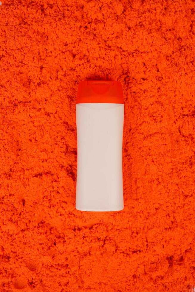 Plastic shampoo bottle with flip-top lid isolated on orange sand background. MockUp template for your design. Empty and clean packaging for cosmetic product. File contains clipping path. photo