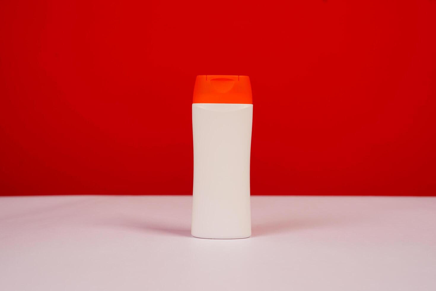 Plastic shampoo bottle with flip-top lid isolated on red and white background. MockUp template for your design. Empty and clean packaging for cosmetic product. File contains clipping path. photo