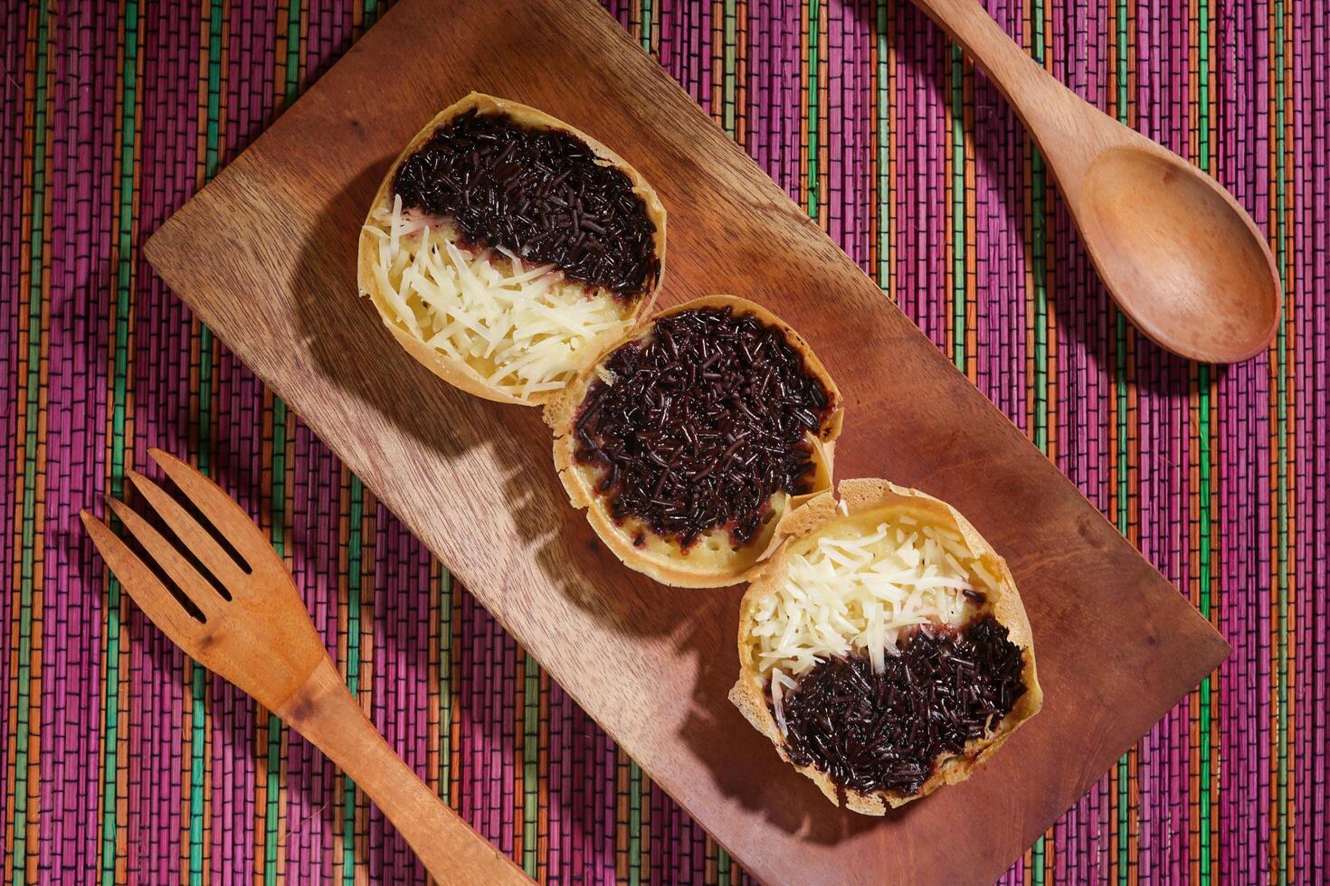 Martabak mini or terang bulan mini is Indonesian popular street food, made from flour, egg, yeast, topped with cheese or chocolate. Mini sweet martabak placed on a rainbow-colored mat photo