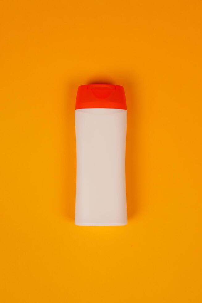 Plastic shampoo bottle with flip-top lid isolated on orange background. MockUp template for your design. Empty and clean packaging for cosmetic product. File contains clipping path. photo