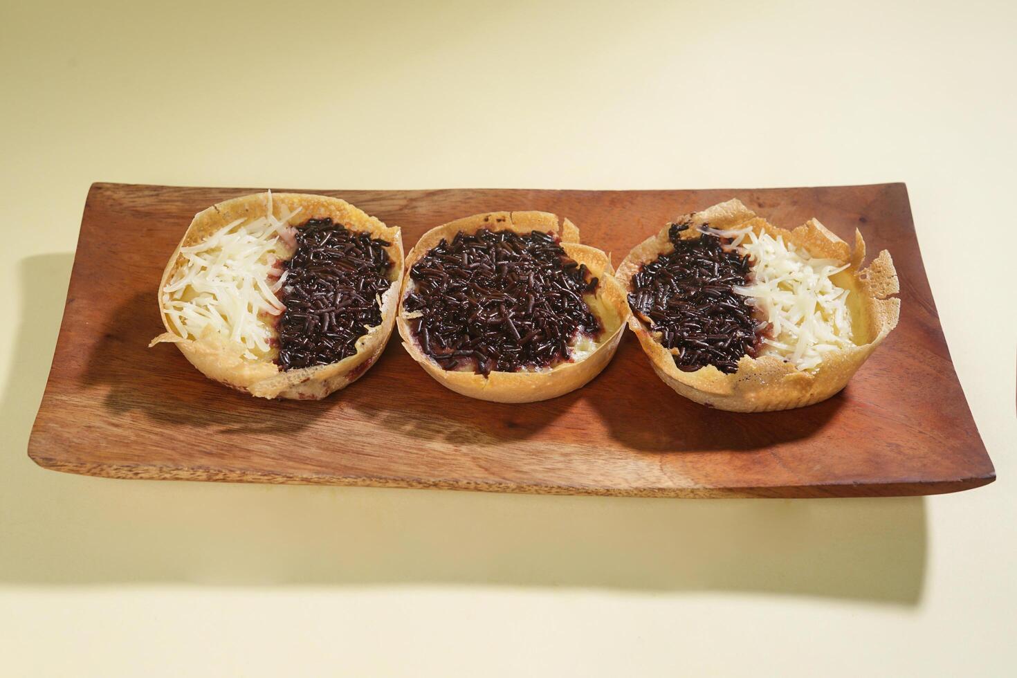 Martabak mini or terang bulan mini is Indonesian popular street food, made from flour, egg, yeast, topped with cheese or chocolate. Mini sweet martabak isolated on yellow background. photo