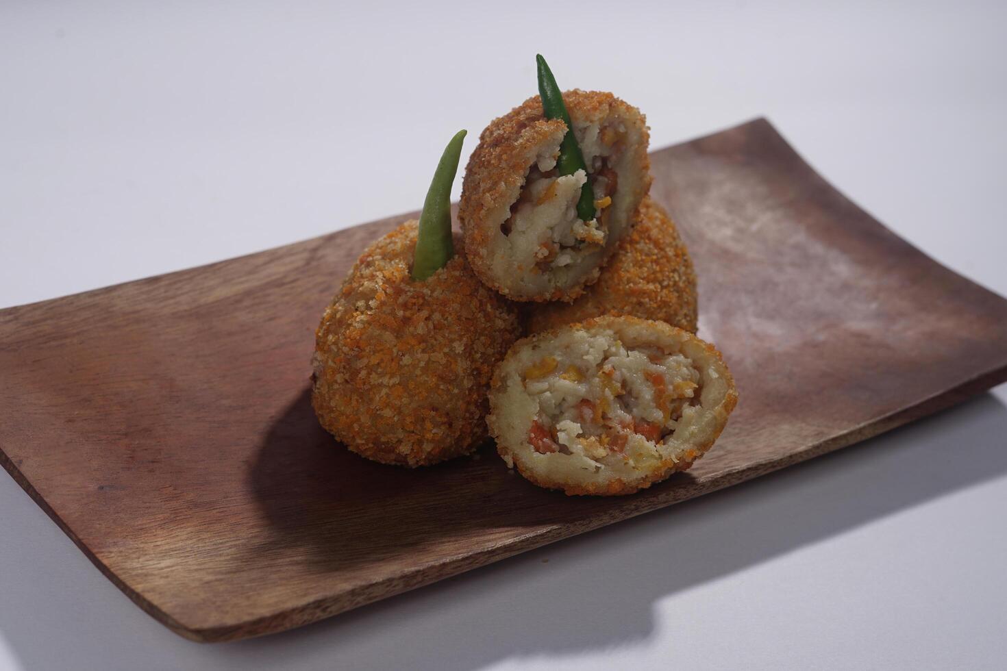 Delicious Indonesian snack named Risol or Risoles filled with smoked beef mayonnaise and crispy fried bread crumb texture on a wooden plate, isolated on a white background photo