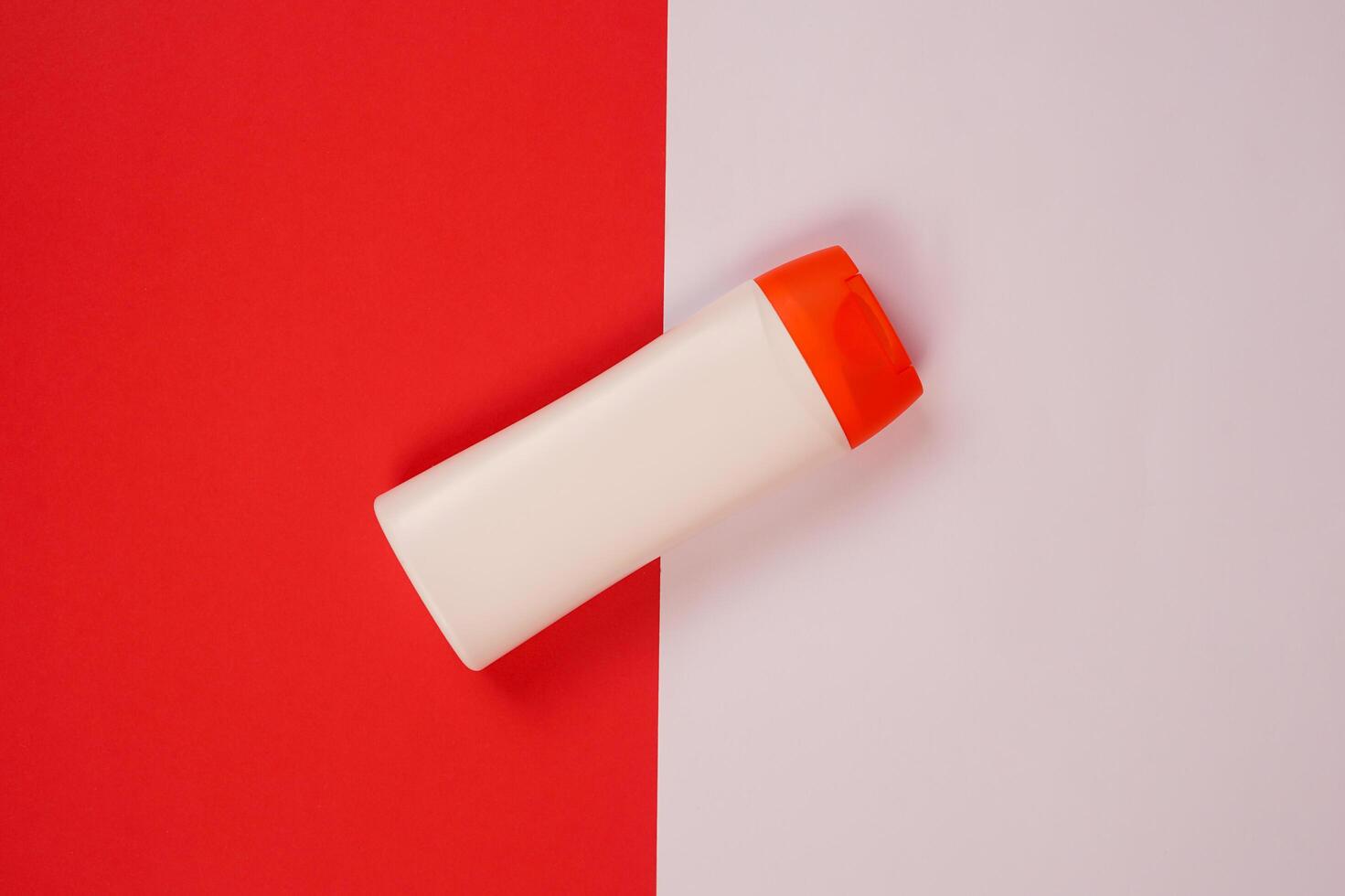 Plastic shampoo bottle with flip-top lid isolated on red and white background. MockUp template for your design. Empty and clean packaging for cosmetic product. File contains clipping path. photo