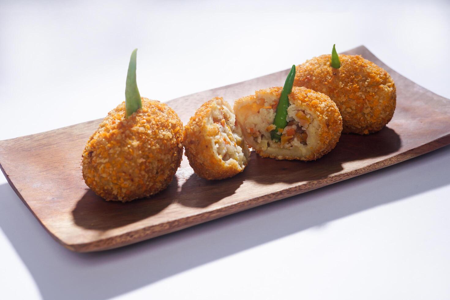 Delicious Indonesian snack named Risol or Risoles filled with smoked beef mayonnaise and crispy fried bread crumb texture on a wooden plate, isolated on a white background photo