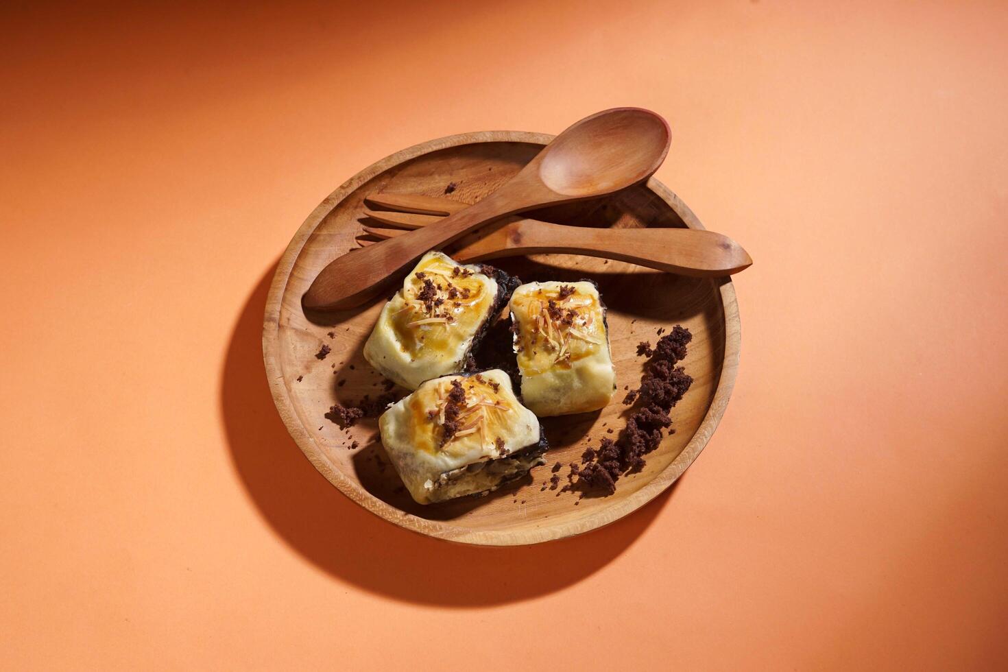 Banana Bolen is made from bananas and pastry dough, filled with chocolate and cheese. It is served on a wooden plate in a selective focus style image. photo