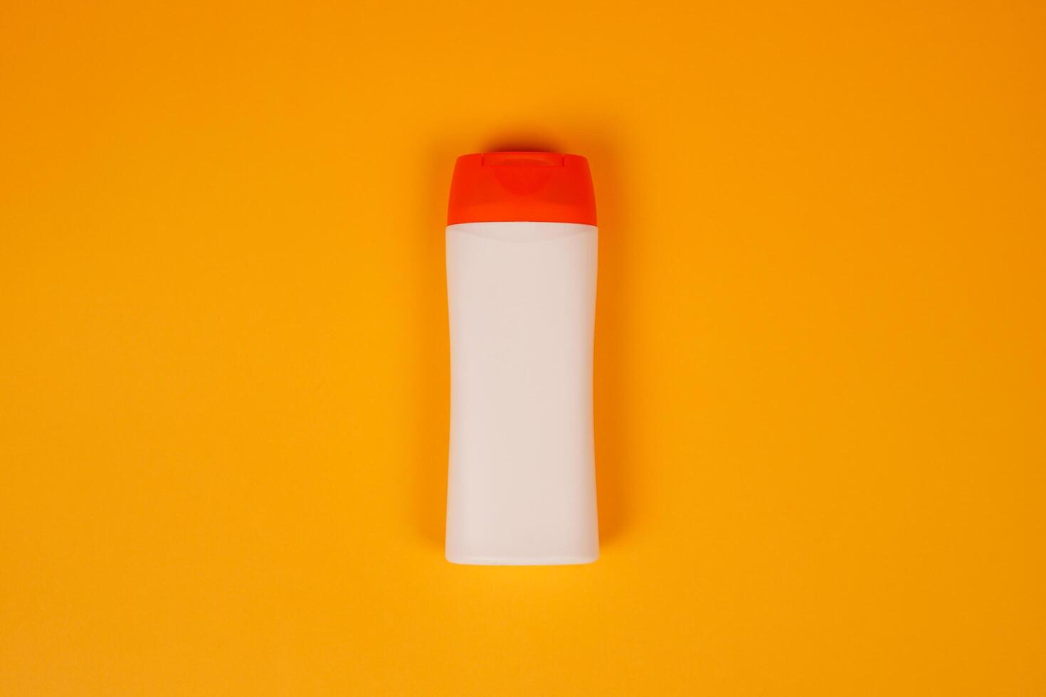 Plastic shampoo bottle with flip-top lid isolated on orange background. MockUp template for your design. Empty and clean packaging for cosmetic product. File contains clipping path. photo
