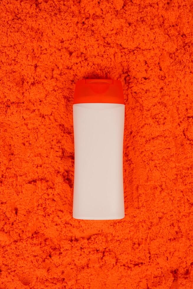 Plastic shampoo bottle with flip-top lid isolated on orange sand background. MockUp template for your design. Empty and clean packaging for cosmetic product. File contains clipping path. photo