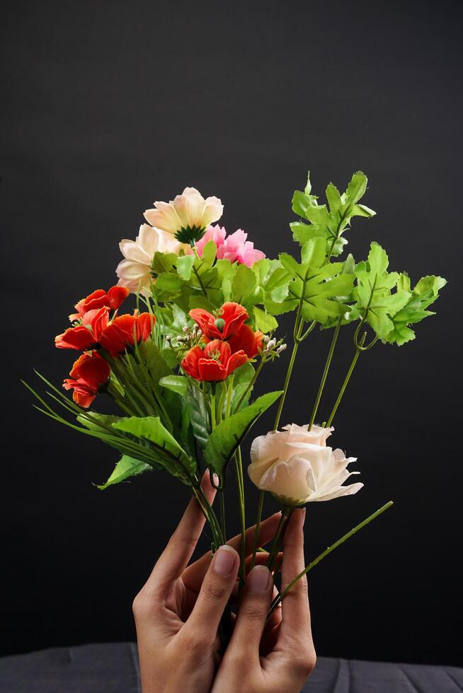 Hand holding red and white spring flowers on black background. High resolution photo. Selective focus. photo