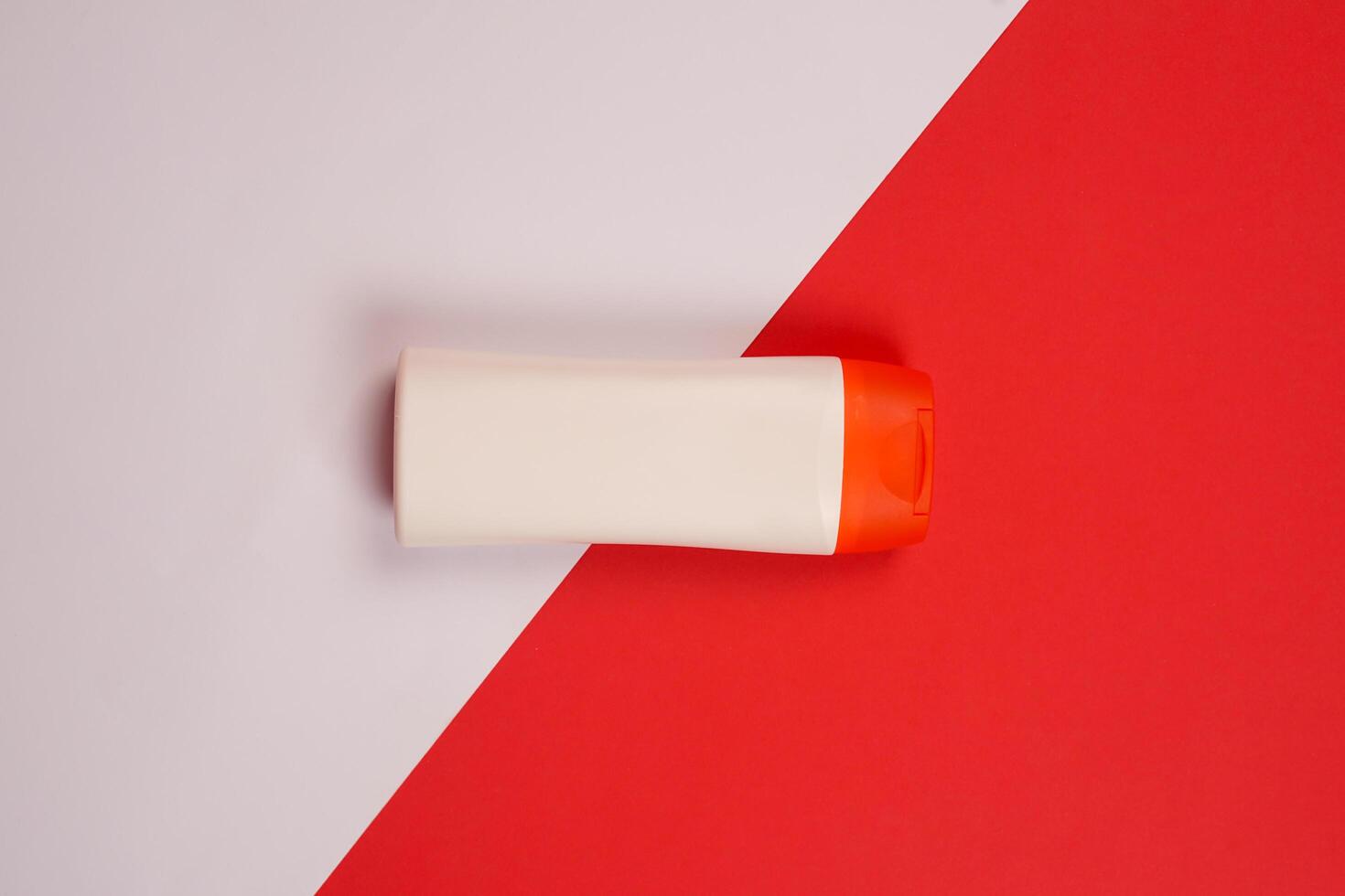 Plastic shampoo bottle with flip-top lid isolated on red and white background. MockUp template for your design. Empty and clean packaging for cosmetic product. File contains clipping path. photo