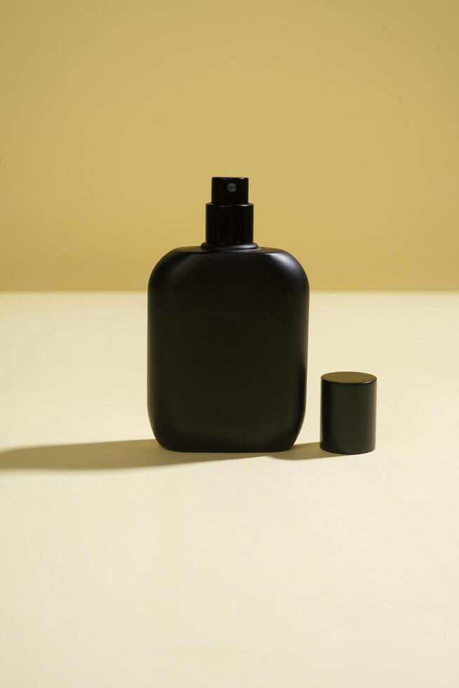 Perfume bottle with black spray on yellow background. High resolution photo. photo