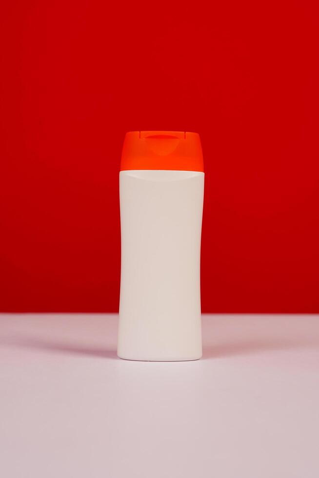 Plastic shampoo bottle with flip-top lid isolated on red and white background. MockUp template for your design. Empty and clean packaging for cosmetic product. File contains clipping path. photo