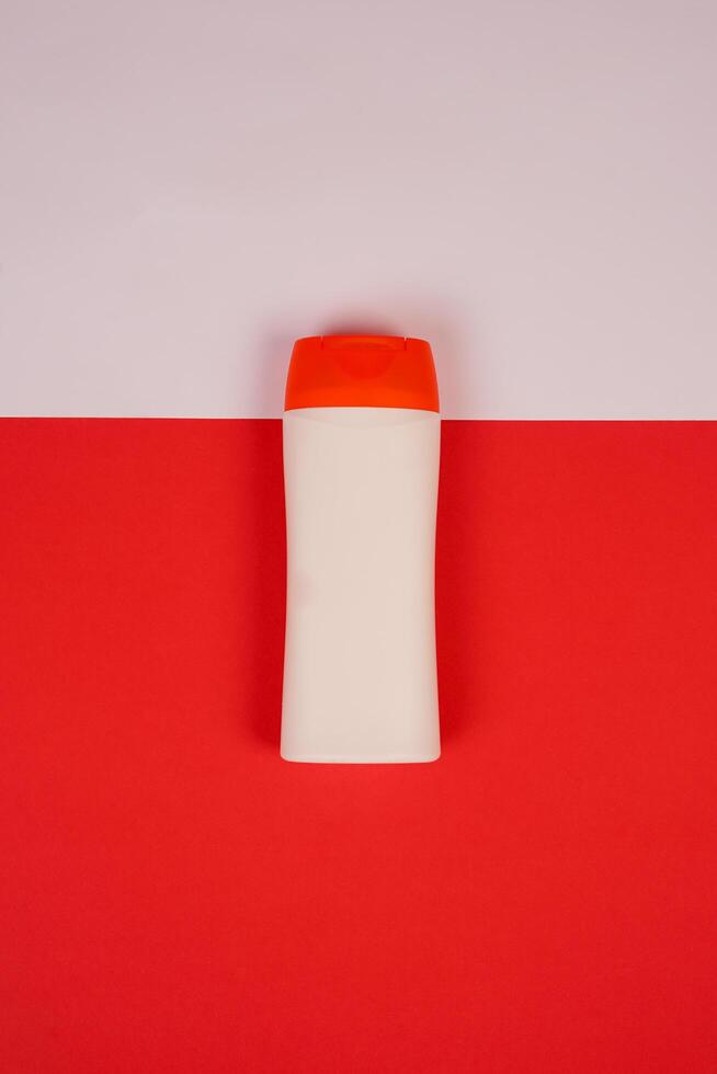 Plastic shampoo bottle with flip-top lid isolated on red and white background. MockUp template for your design. Empty and clean packaging for cosmetic product. File contains clipping path. photo