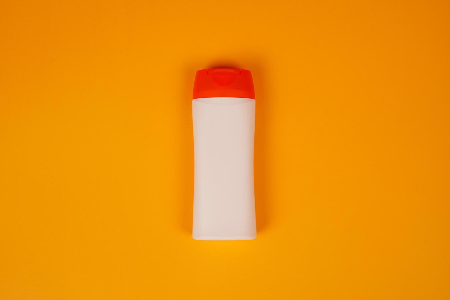 Plastic shampoo bottle with flip-top lid isolated on orange background. MockUp template for your design. Empty and clean packaging for cosmetic product. File contains clipping path. photo