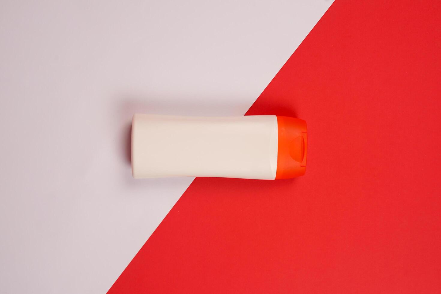 Plastic shampoo bottle with flip-top lid isolated on red and white background. MockUp template for your design. Empty and clean packaging for cosmetic product. File contains clipping path. photo