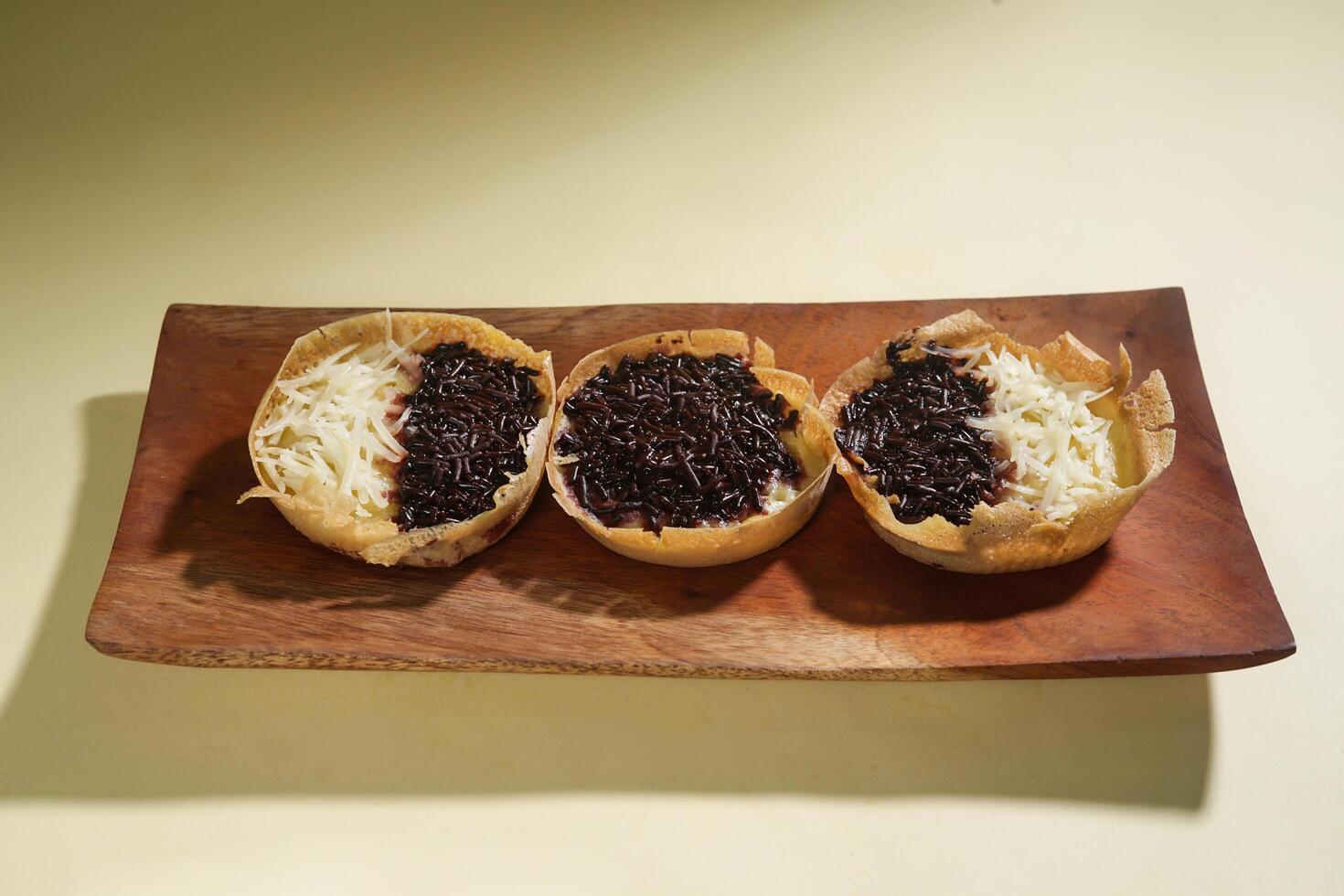Martabak mini or terang bulan mini is Indonesian popular street food, made from flour, egg, yeast, topped with cheese or chocolate. Mini sweet martabak isolated on yellow background. photo