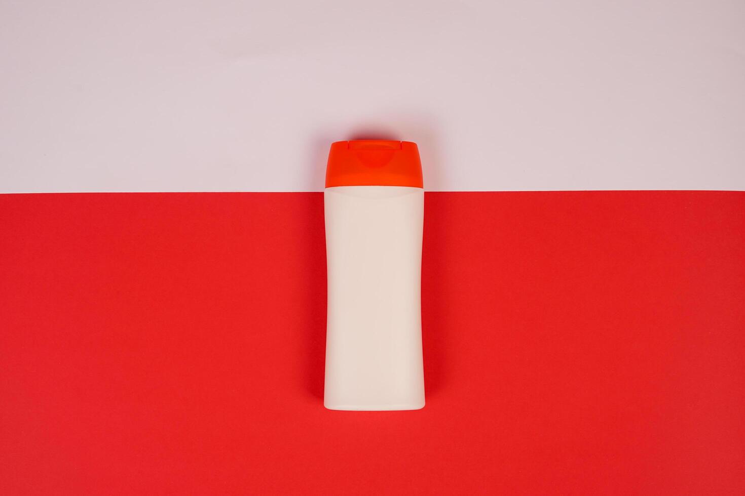 Plastic shampoo bottle with flip-top lid isolated on red and white background. MockUp template for your design. Empty and clean packaging for cosmetic product. File contains clipping path. photo