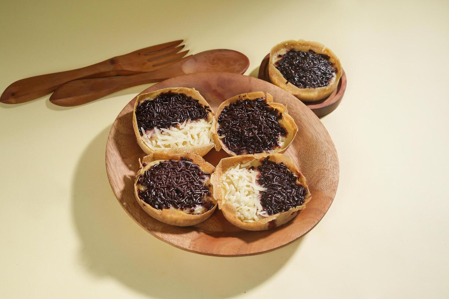 Martabak mini or terang bulan mini is Indonesian popular street food, made from flour, egg, yeast, topped with cheese or chocolate. Mini sweet martabak isolated on yellow background. photo