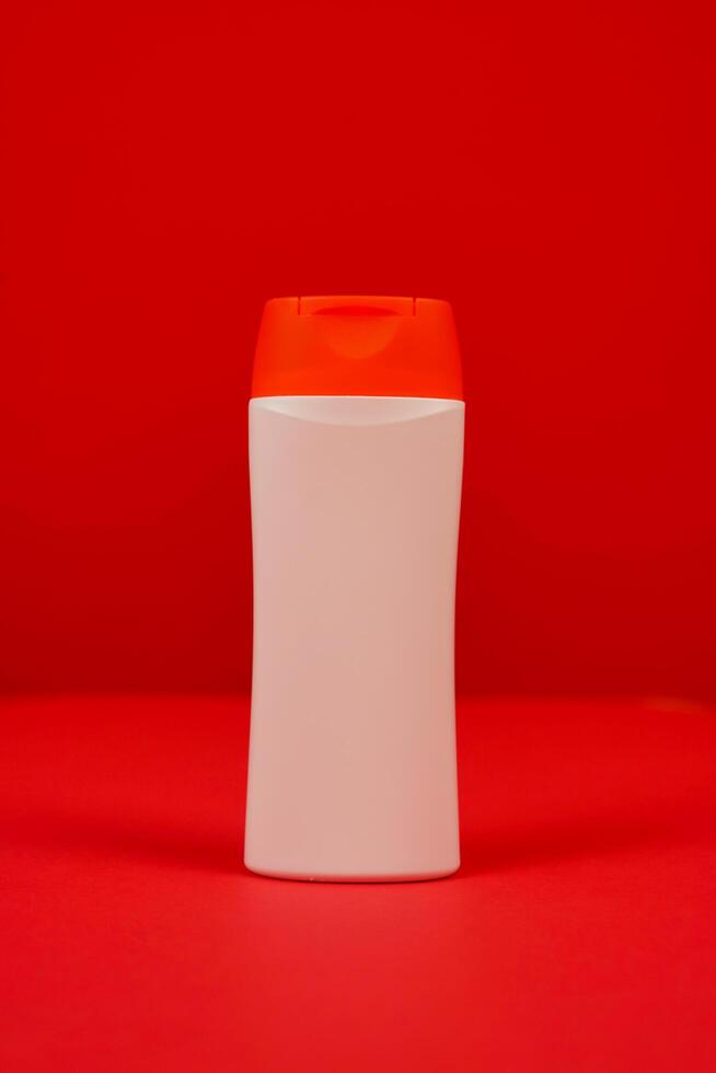 Plastic shampoo bottle with flip-top lid isolated on red background. MockUp template for your design. Empty and clean packaging for cosmetic product. File contains clipping path. photo