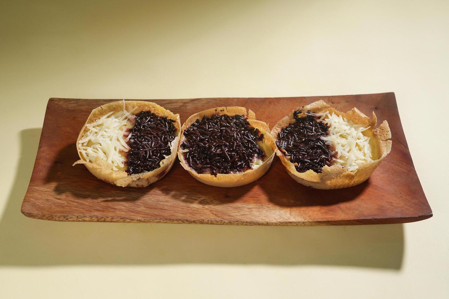 Martabak mini or terang bulan mini is Indonesian popular street food, made from flour, egg, yeast, topped with cheese or chocolate. Mini sweet martabak isolated on yellow background. photo