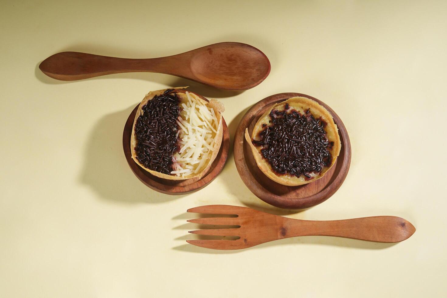 Martabak mini or terang bulan mini is Indonesian popular street food, made from flour, egg, yeast, topped with cheese or chocolate. Mini sweet martabak isolated on yellow background. photo