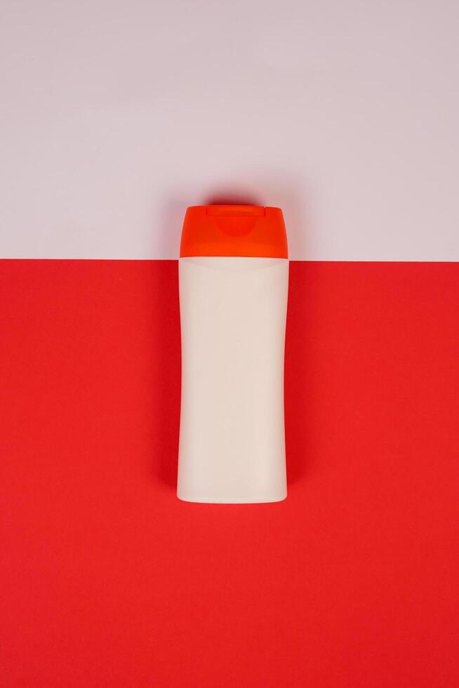 Plastic shampoo bottle with flip-top lid isolated on red and white background. MockUp template for your design. Empty and clean packaging for cosmetic product. File contains clipping path. photo