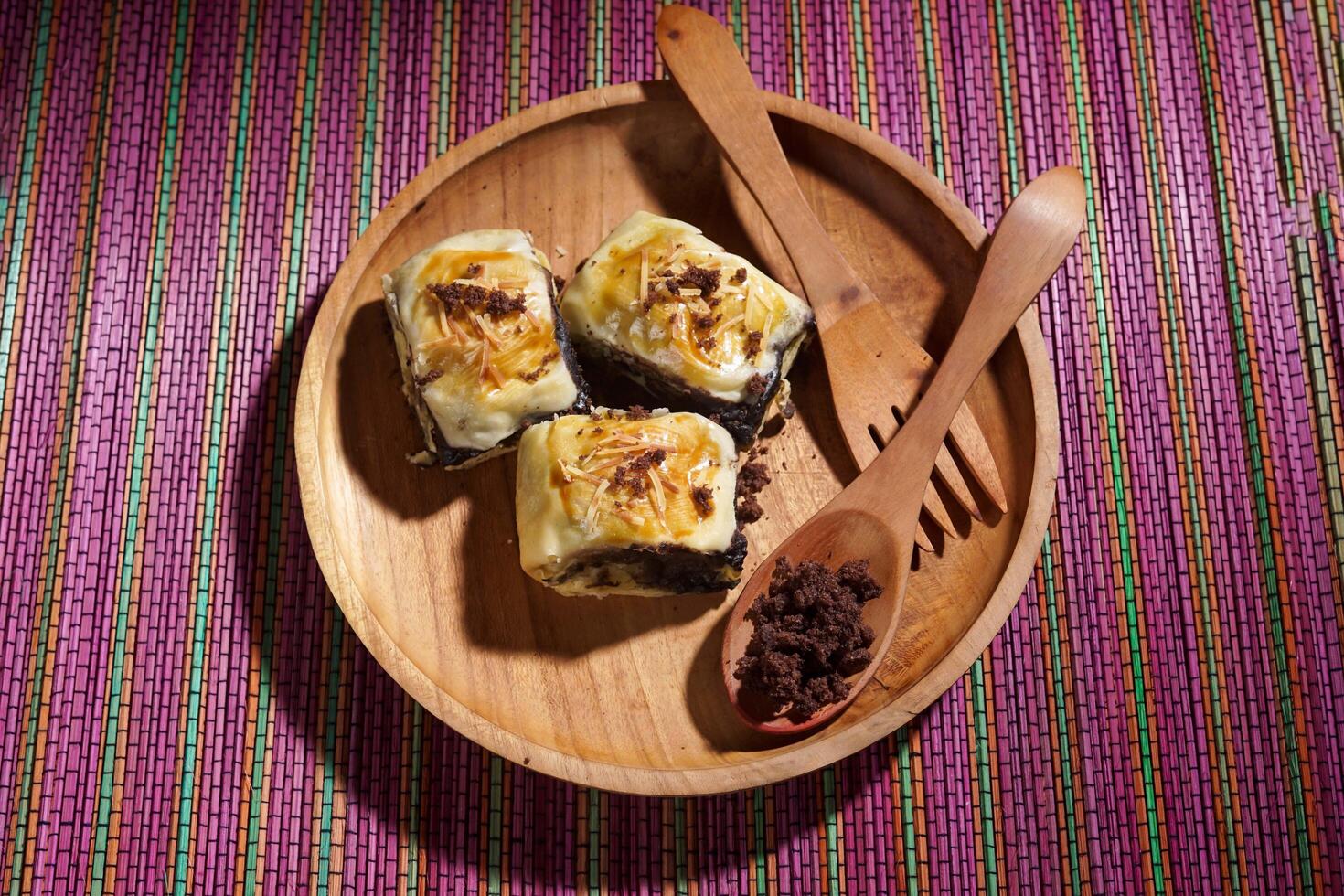 Banana Bolen is made from bananas and pastry dough, filled with chocolate and cheese. It is served on a wooden plate in a selective focus style image. photo