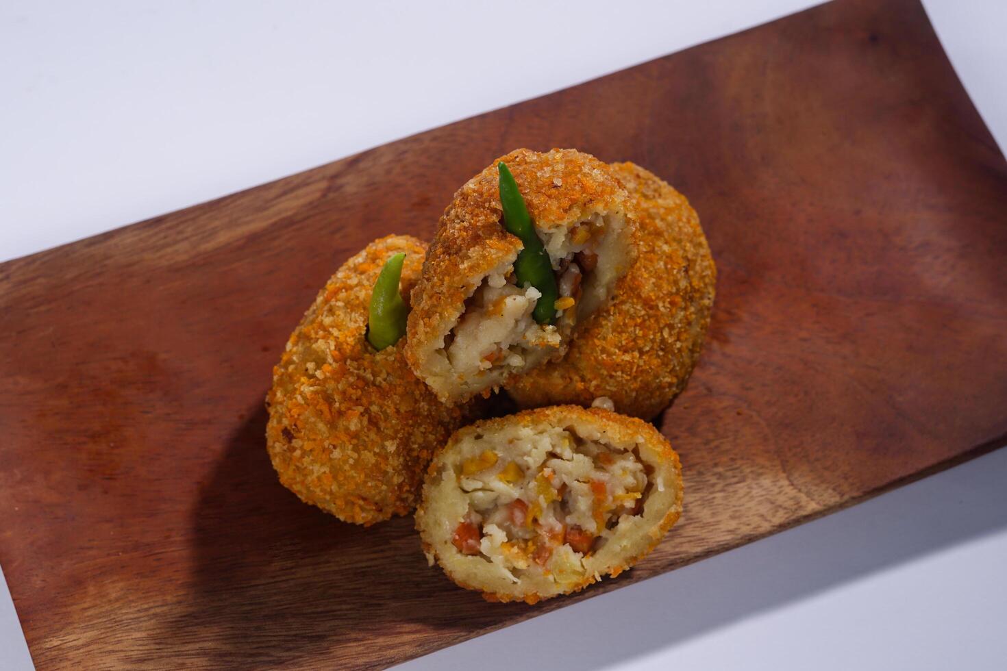 Delicious Indonesian snack named Risol or Risoles filled with smoked beef mayonnaise and crispy fried bread crumb texture on a wooden plate, isolated on a white background photo