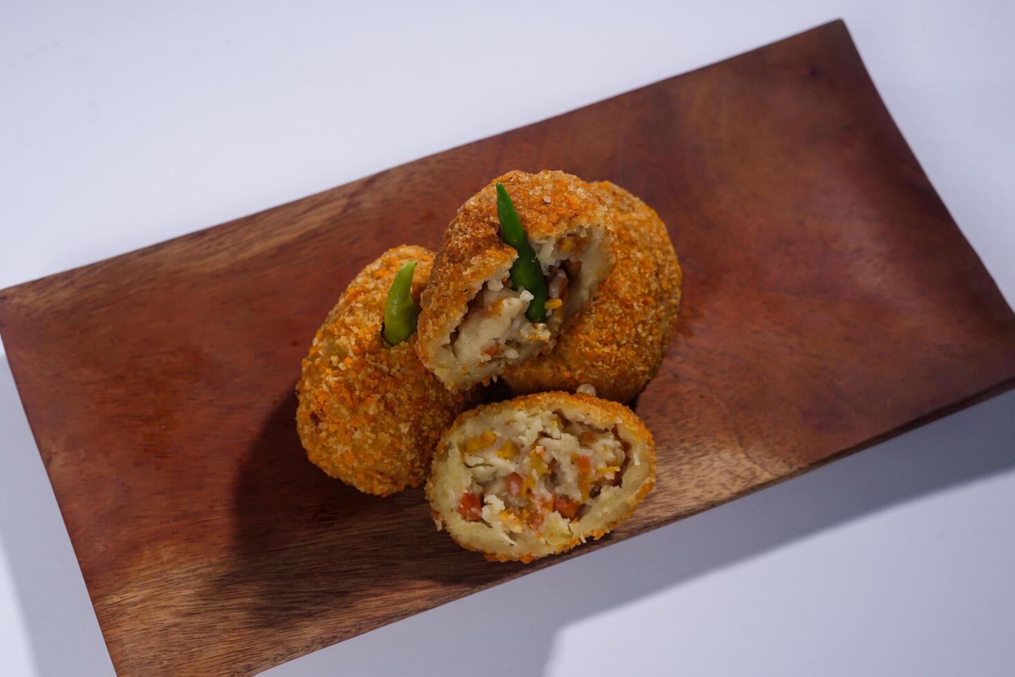 Delicious Indonesian snack named Risol or Risoles filled with smoked beef mayonnaise and crispy fried bread crumb texture on a wooden plate, isolated on a white background photo