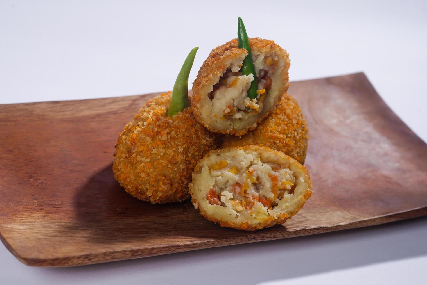 Delicious Indonesian snack named Risol or Risoles filled with smoked beef mayonnaise and crispy fried bread crumb texture on a wooden plate, isolated on a white background photo